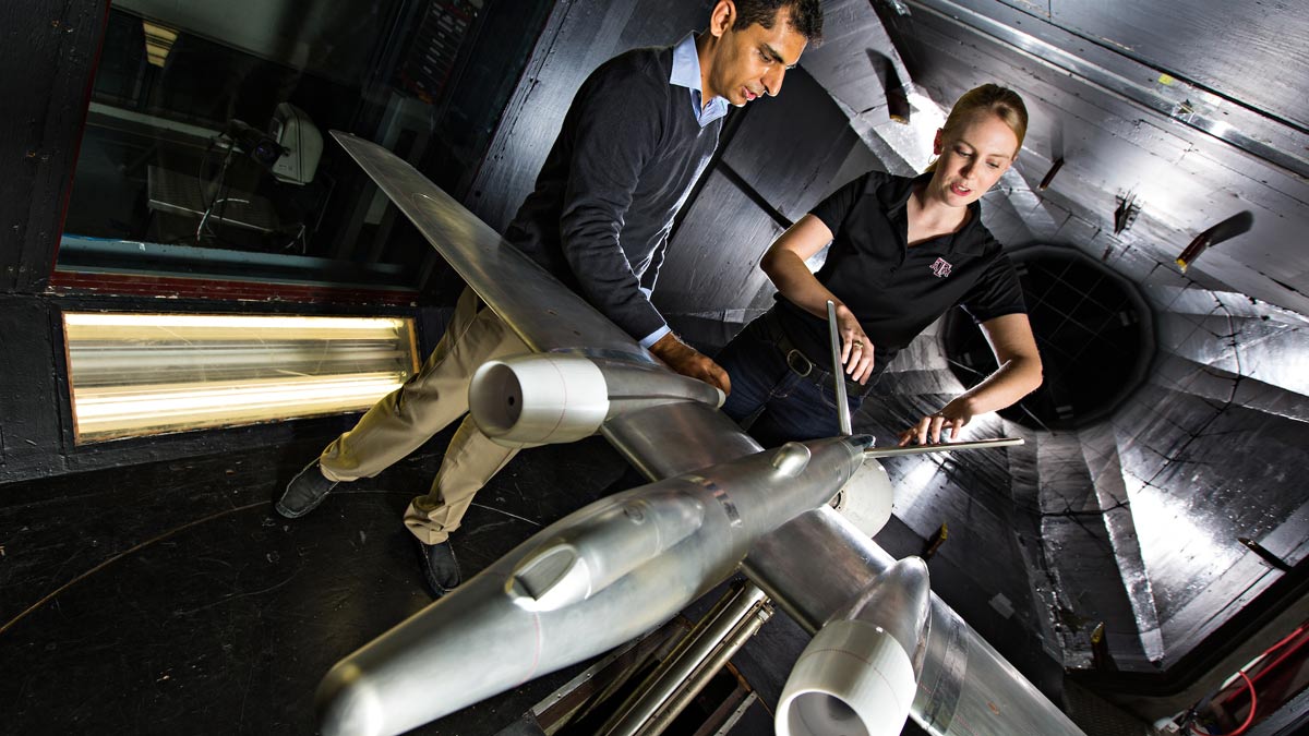 Two researchers examine an airplane miniature in the low speed wind tunnel