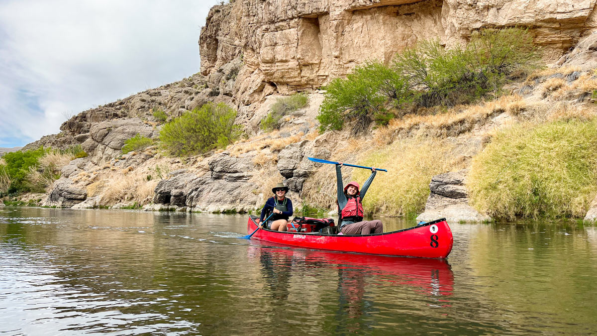 Two students kayak on a river