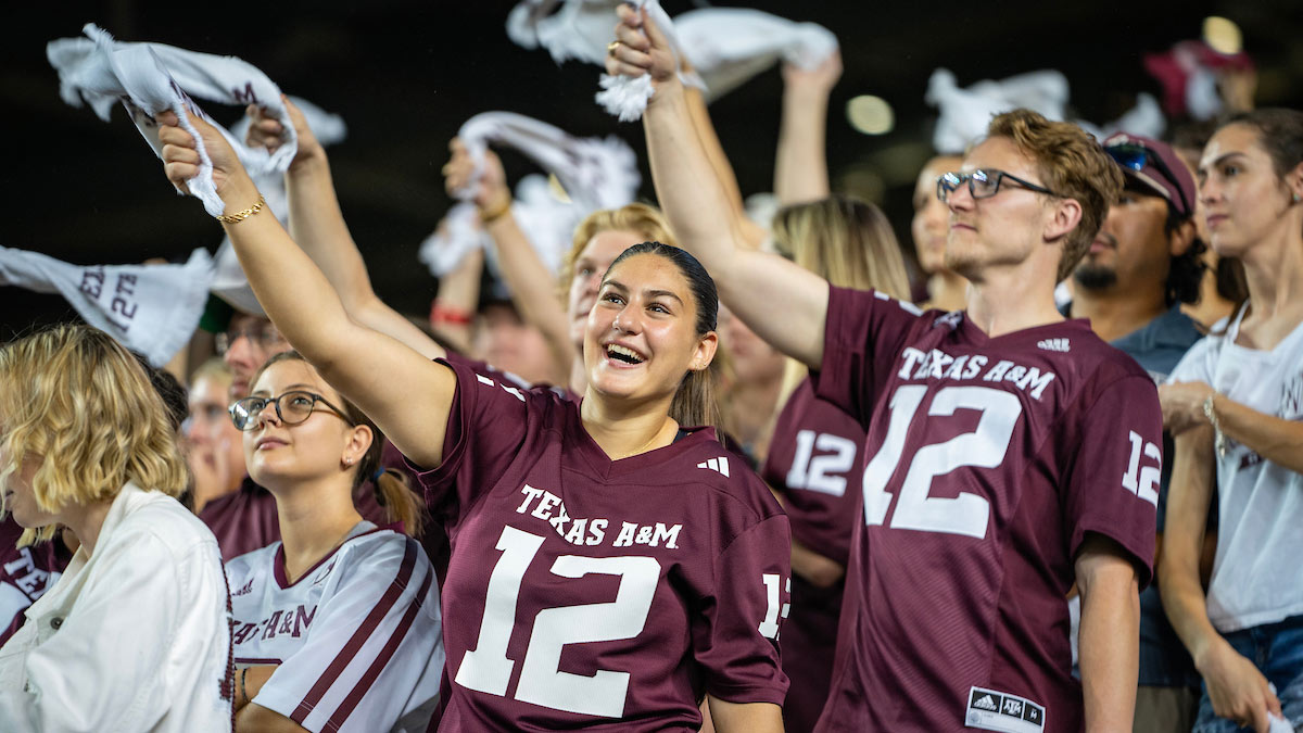 Two Aggies in 12th Man jerseys swing 12th Man towels