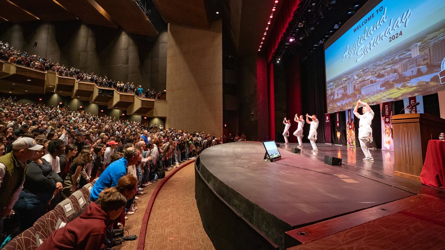 A lively audience engages with speakers on stage during a conference event in a large auditorium.