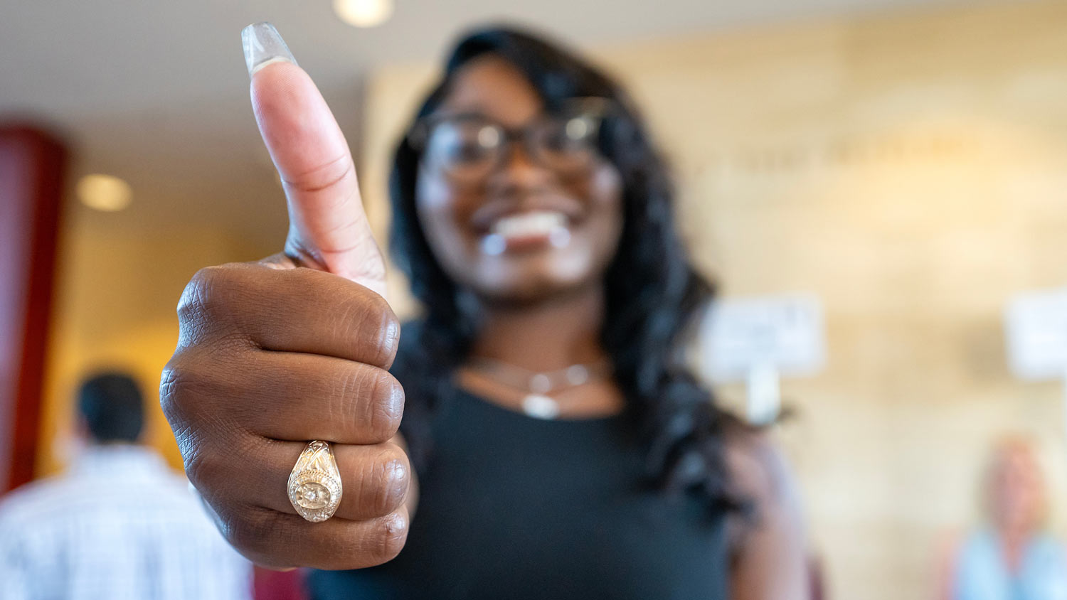 Close up of an Aggie ring on a student's hand as she gives a Gig 'Em