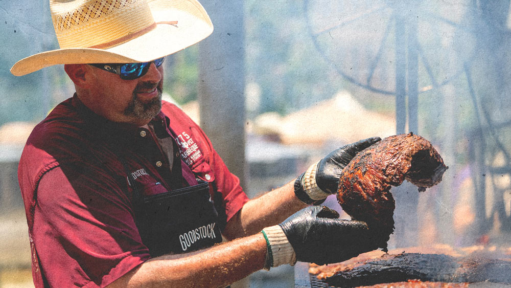 Aggie Barbecuer checks a rack of ribs over a smoking grill