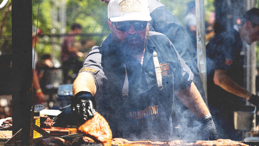 Barbecue Specialist checking his work over a smoking grill 