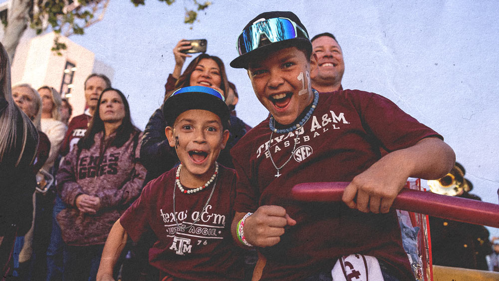 Two young Texas A&M fans smiling and cheering before gameday