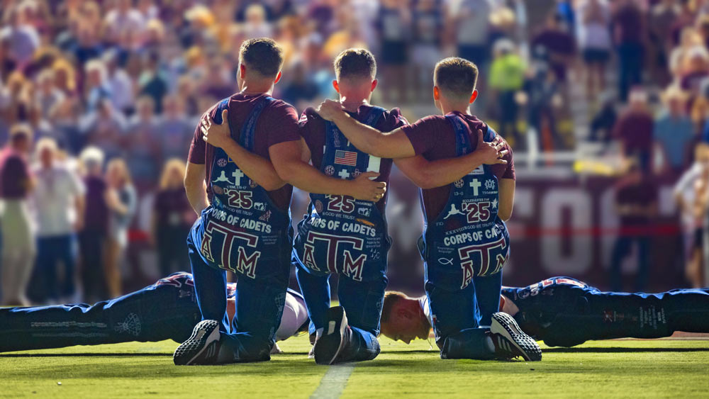 Yell Leaders at Midnight Yell kneeling on the 50 yard line of the football field with their backs to the camera.